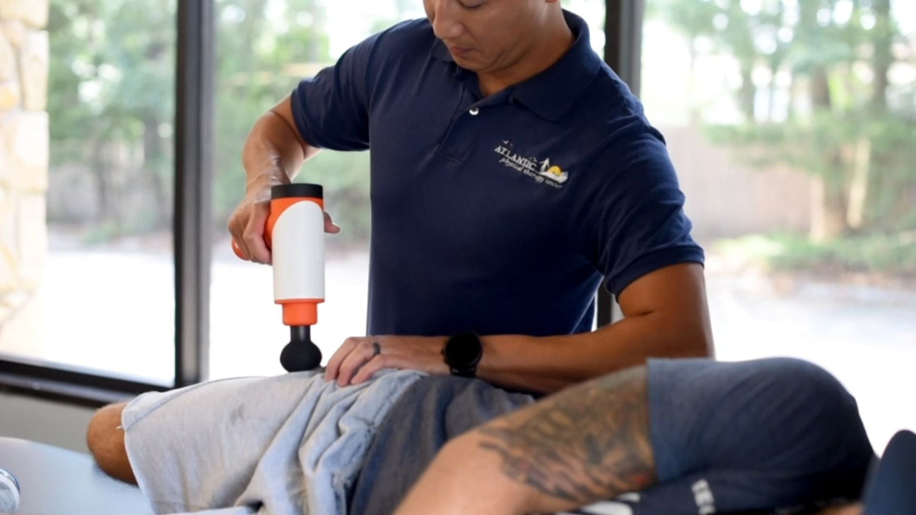 physical therapist using massage gun on patient