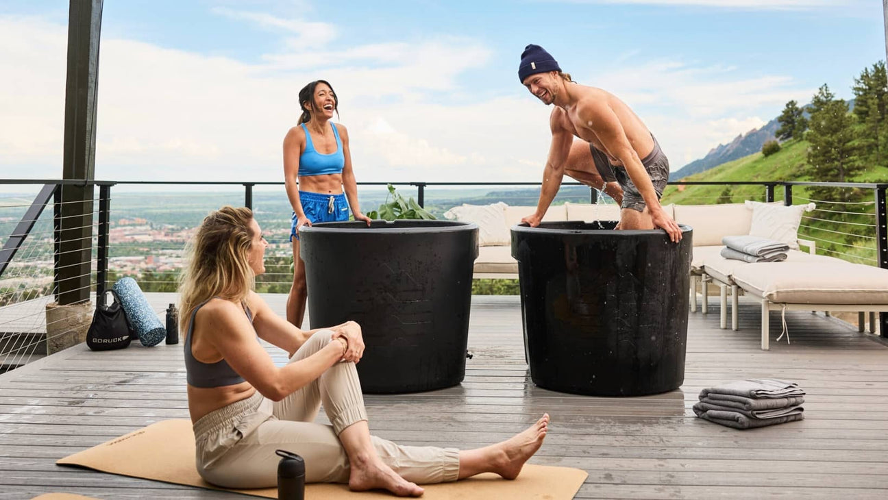man smiling and woman laughing as he takes the cold plunge using ice barrel tub