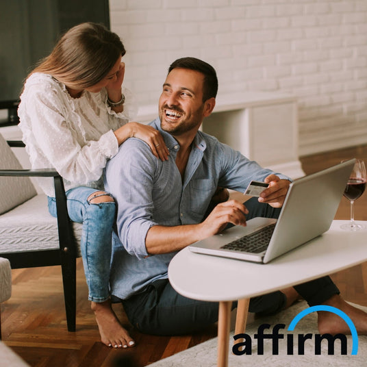 couple smiling and laughing at home on laptop with credit card in mans hand