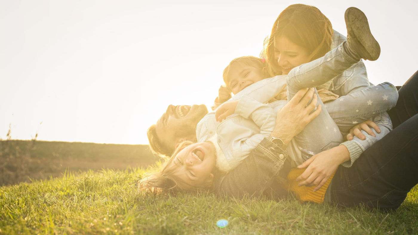 Happy family smiling and laying down on grass during sunset