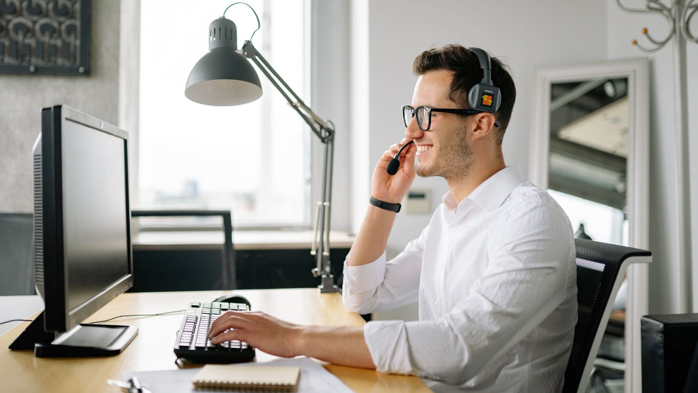 Happy ZiahCare team member at his desk with a headset on talking to a customer