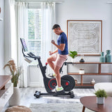 Man using Echelon EX-5s Smart Connect Bike in living room  and lifting 2lb dummbells