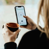 woman using HUUM app while drinking coffee