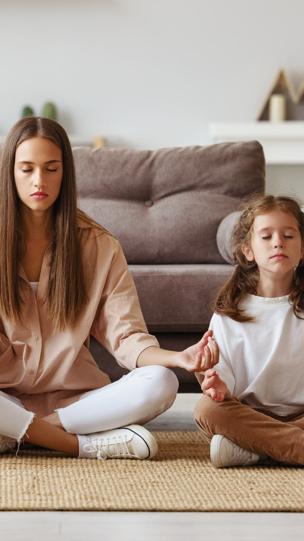Family meditating alongside one another in living room mobile image