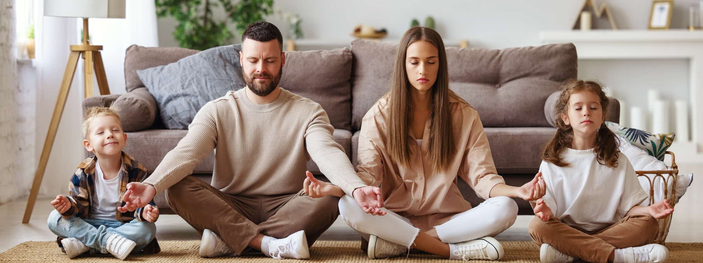 Family meditating alongside one another in living room desktop image