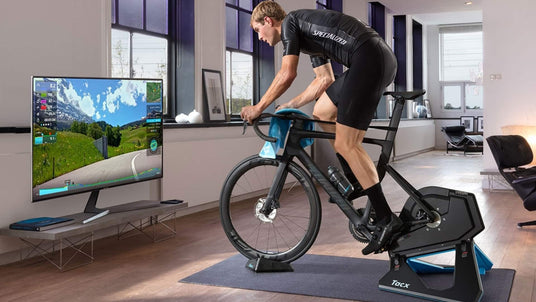 man riding neo tacx 2t trainer in living room