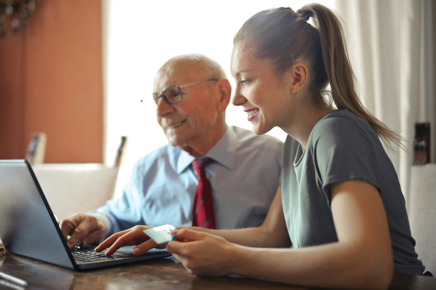 woman and man smiling while looking on laptop with credit card in womans hand
